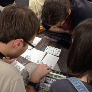 Jugadores resolviendo pruebas en Hotel Conan Doyle, juego colaborativo de misterio y deducción