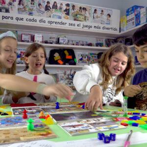 Niños y niñas jugando a Cazatesoros, un juego educativo de mesa que combina lógica, memoria, cálculo mental y visión espacial en una aventura por diferentes países.