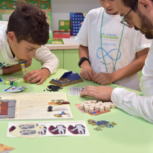 Niños y adultos jugando a La Leyenda del Último Faraón, un juego colaborativo de estrategia, lógica y cálculo con tablero y pirámide 3D